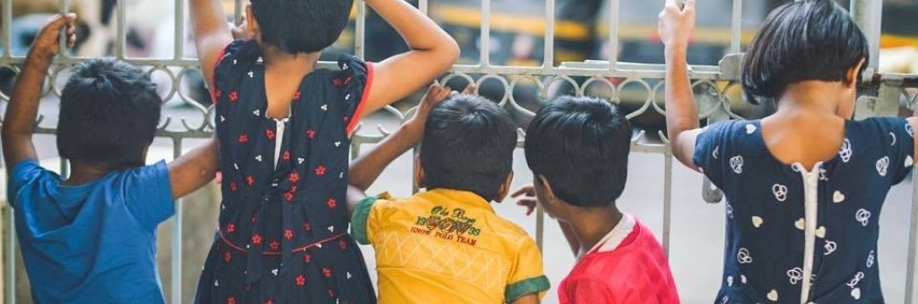 Barn tittar ut genom en gallergrind