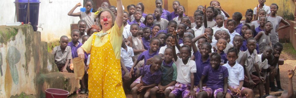 Clown i gula kläder uppträder för en grupp barn