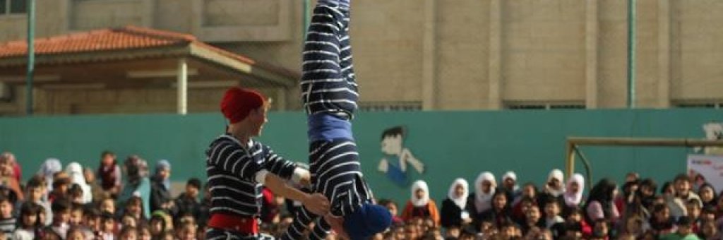 Två clowner utför ett akrobatiskt nummer inför en stor publik