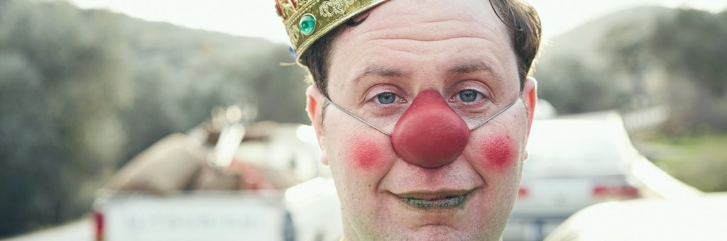 Närbild på clown i röd näsa och krona