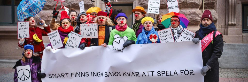 En samling clowner i färgglada skyltar och banderollen "Snart finns inga barn kvar att spela för"