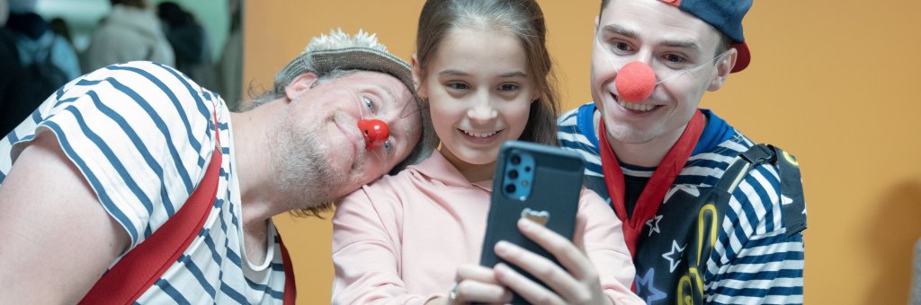 En flicka tar en bild med två clowner med sin mobil