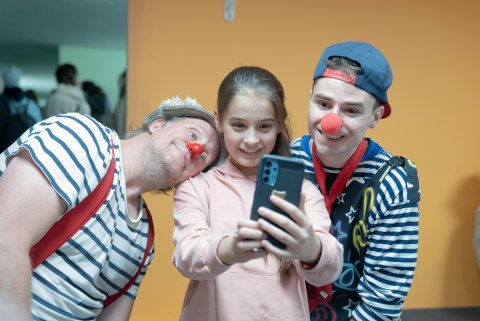 Ett barn tar en selfie med telefonen med två clowner