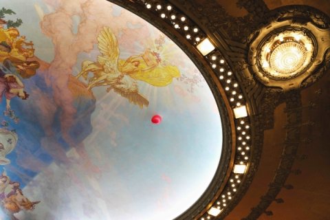 En röd ballong som svävar i Dramatens tak