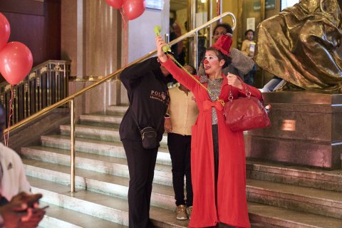 En artist håller upp en gammaldags telefon med sladd och låtsas ta en selfie med ett par barn