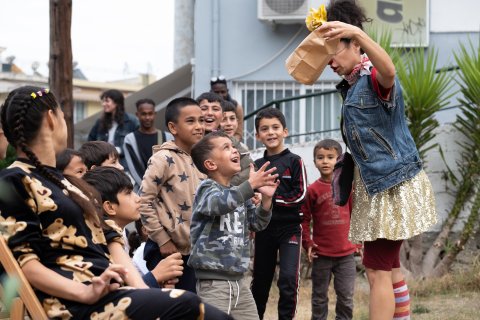 Artist som trollar framför en grupp barn som gapar och skrattar av förvåning