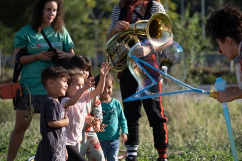 Skrattande barn leker med en stor såpbubbla artister blåser