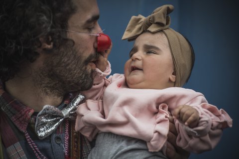 Artist med liten bebis som greppar clownnäsan