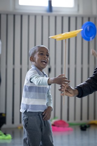 En liten pojke testar att snurra tallrik med ett stort leende