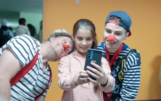 En flicka tar en bild med två clowner med sin mobil