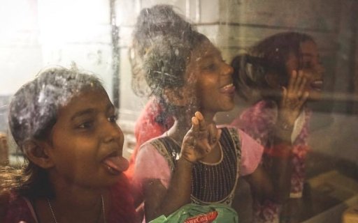 Tre flickor bakom en glasruta gör miner och skrattar