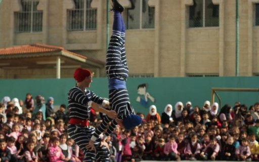 Två clowner utför ett akrobatiskt nummer inför en stor publik