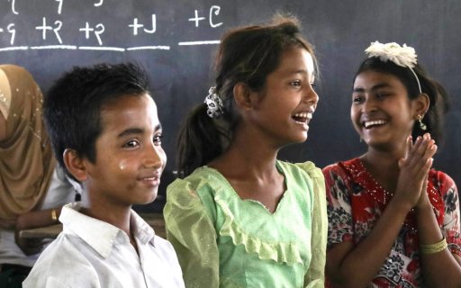 Glada pojkar och flickor i skolan framför svarta tavlan