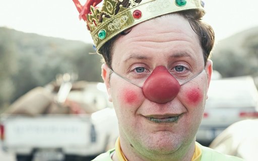 Närbild på clown i röd näsa och krona