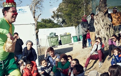 Clown i gröna kläder och krona uppträder för en grupp barn