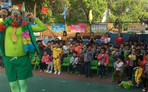 Clown i gröna kläder uppträder inför en publik av barn