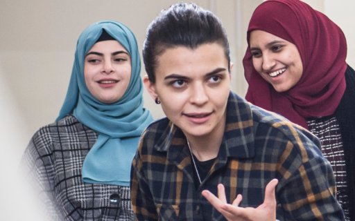 Ranin under en workshop, gestikulerar med händerna, i bakgrunden står två kvinnor i hijab och ler 